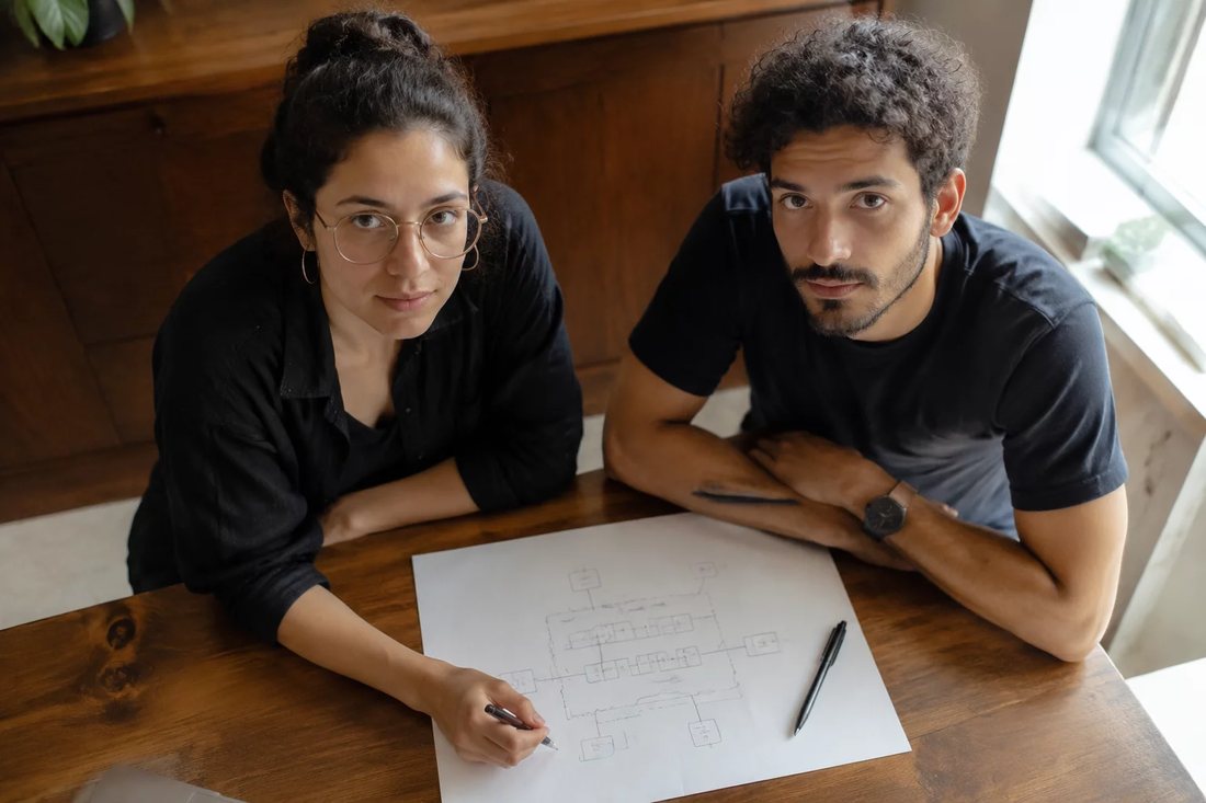 Dupla relendo anotações num tablet apoiado sobre a mesa de madeira